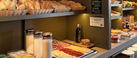 Ein Frühstücksbuffet mit verschiedenen Brotsorten, Milchprodukten und Beilagen.