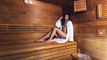 Una sauna con bancos de madera, un balde de madera y un reloj en la pared.