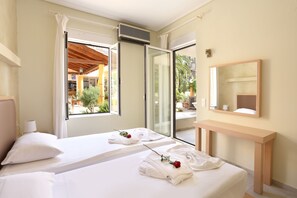 A hotel room with two beds, a large window, a sliding glass door, a wooden bench, and a mirror. - Elma's Dream Apartments (Chania)