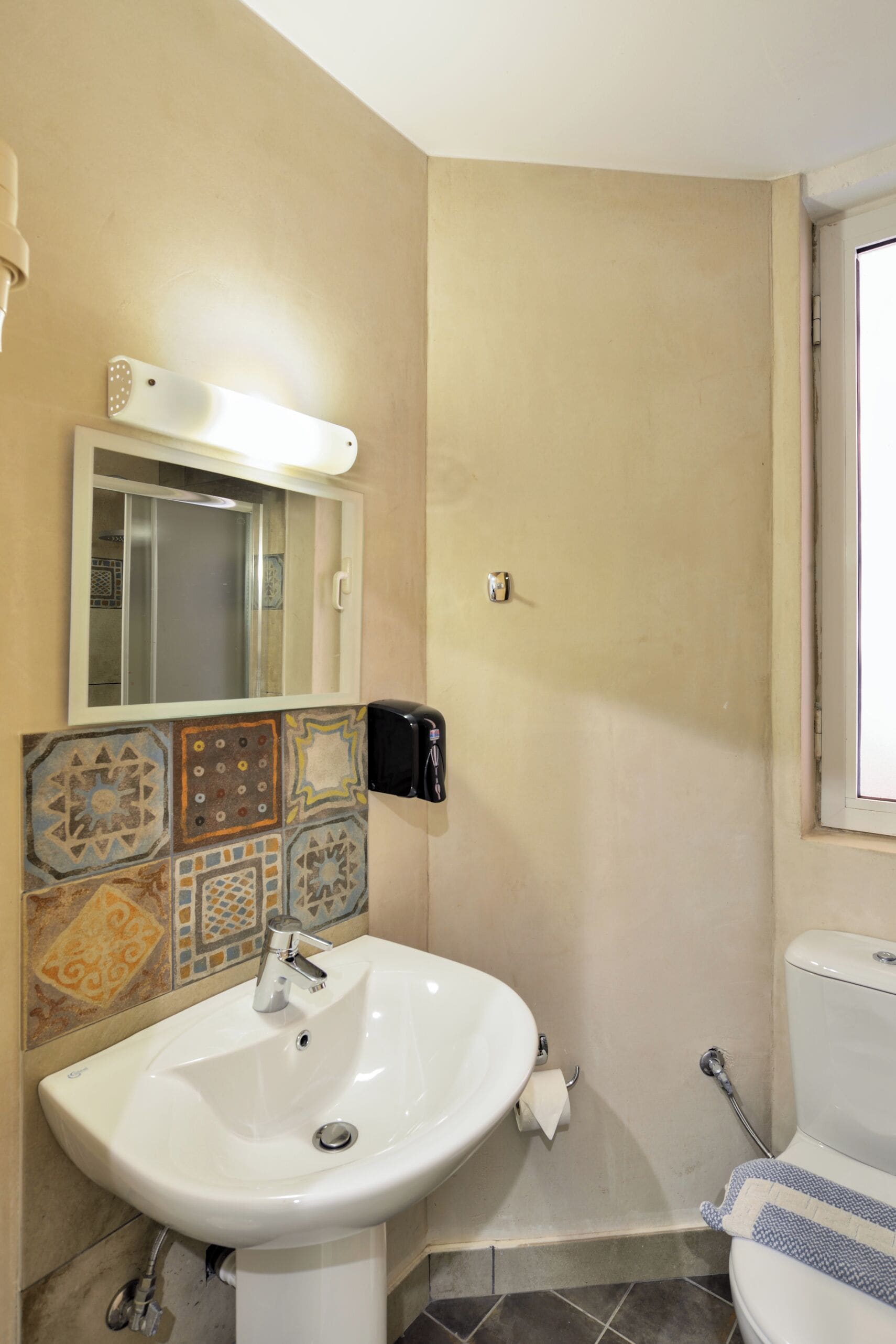 Un baño con lavamanos blanco, espejo, inodoro y ducha.