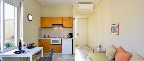 A compact living space with a kitchenette, dining area, and a sofa.