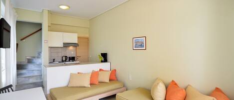 A compact living space with a sofa, a dining table, and a kitchenette.