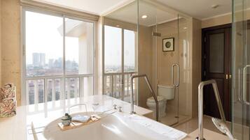 A modern bathroom with a large bathtub, a glass-enclosed shower, and a toilet.