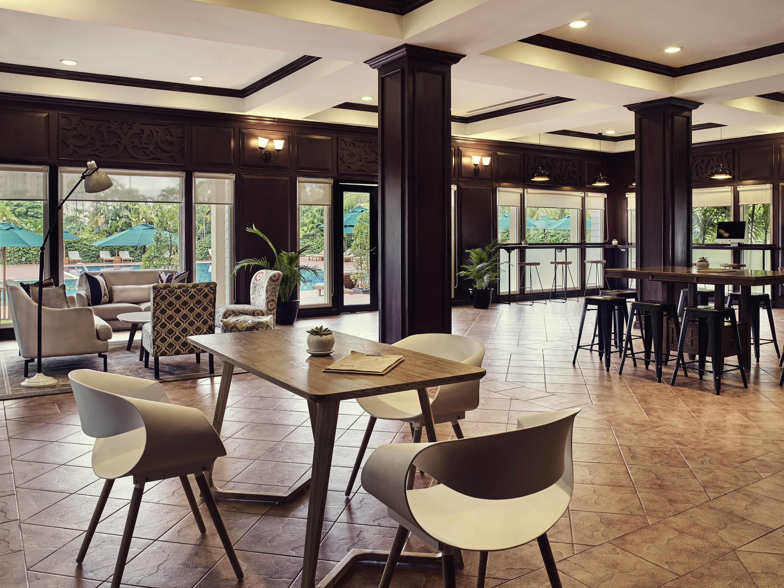 A spacious indoor area with a large table, several chairs, and a view of the outdoors through large windows.