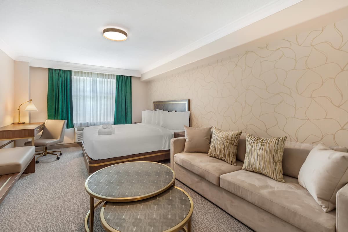 A hotel room with a bed, a sofa, a desk, and a round table.