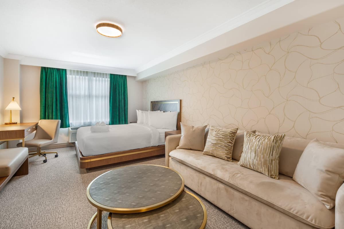 A hotel room with a bed, a sofa, a desk, and a round table.