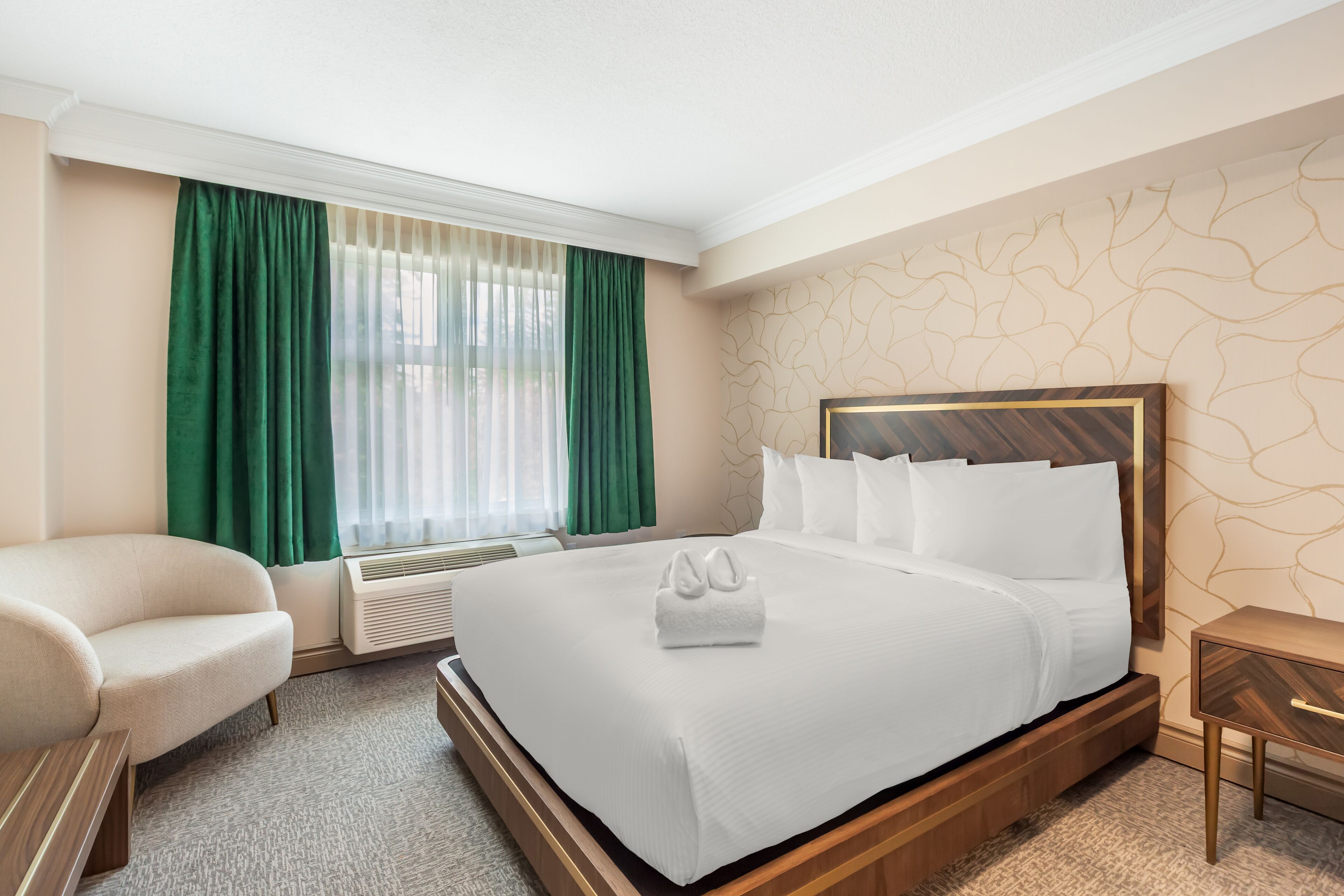 Une chambre d’hôtel avec un grand lit, une chaise, un bureau et une fenêtre avec des rideaux verts.
