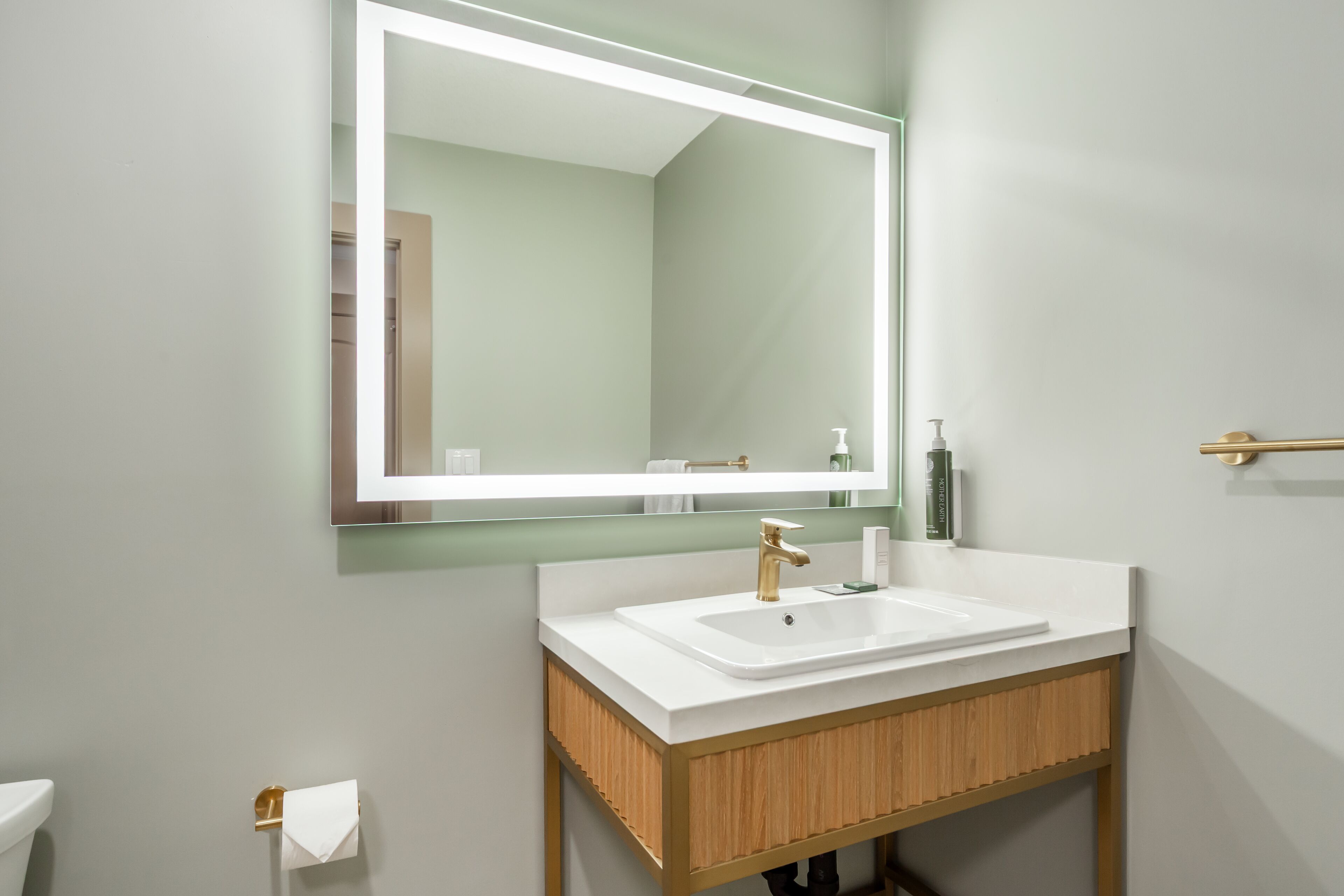Een badkamer met een wit wastafel, een spiegel en een toilet.