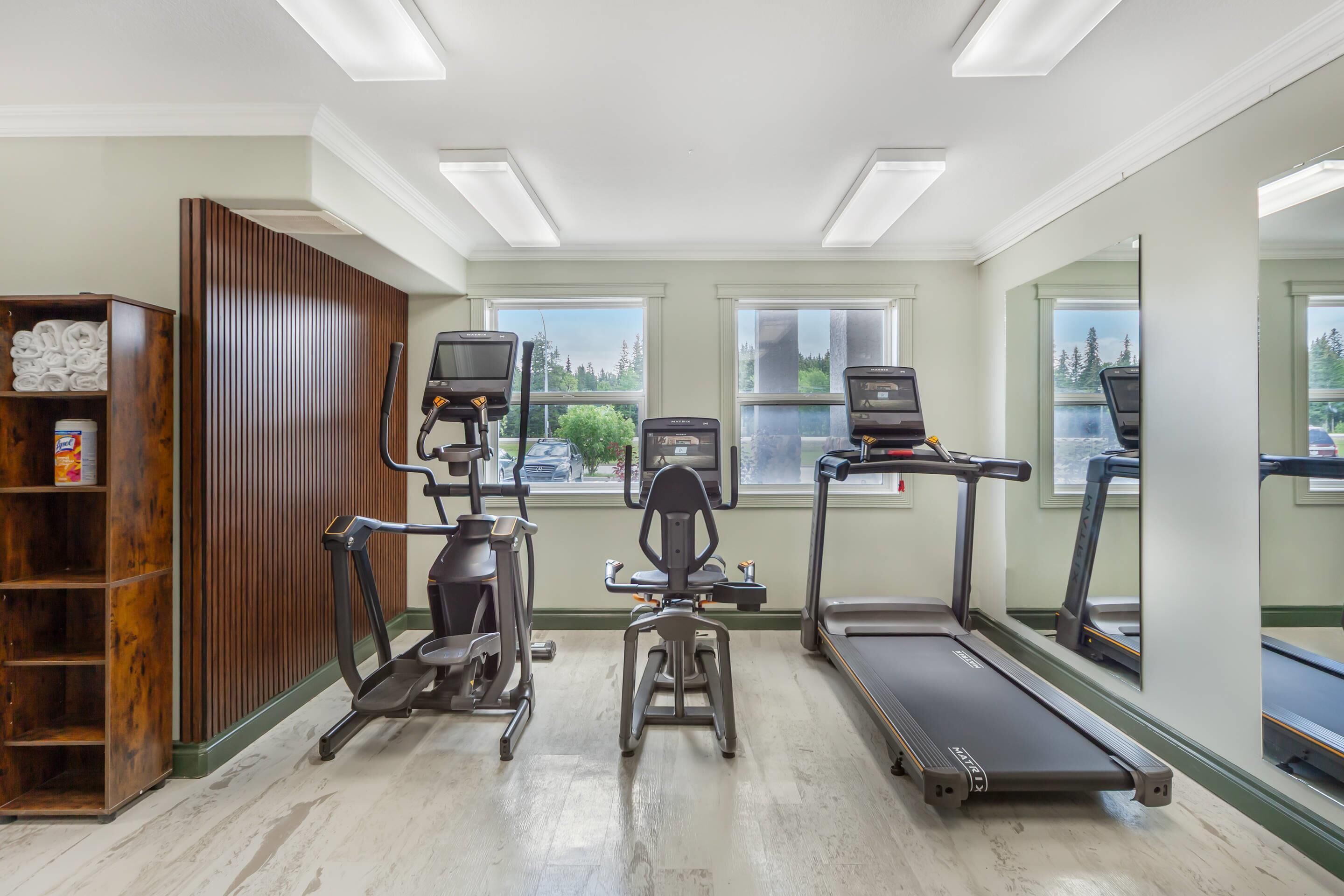Un gimnasio con cintas de correr, elíptica y bicicleta estática.