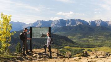 A mountain view with a signboard and two people standing beside it.