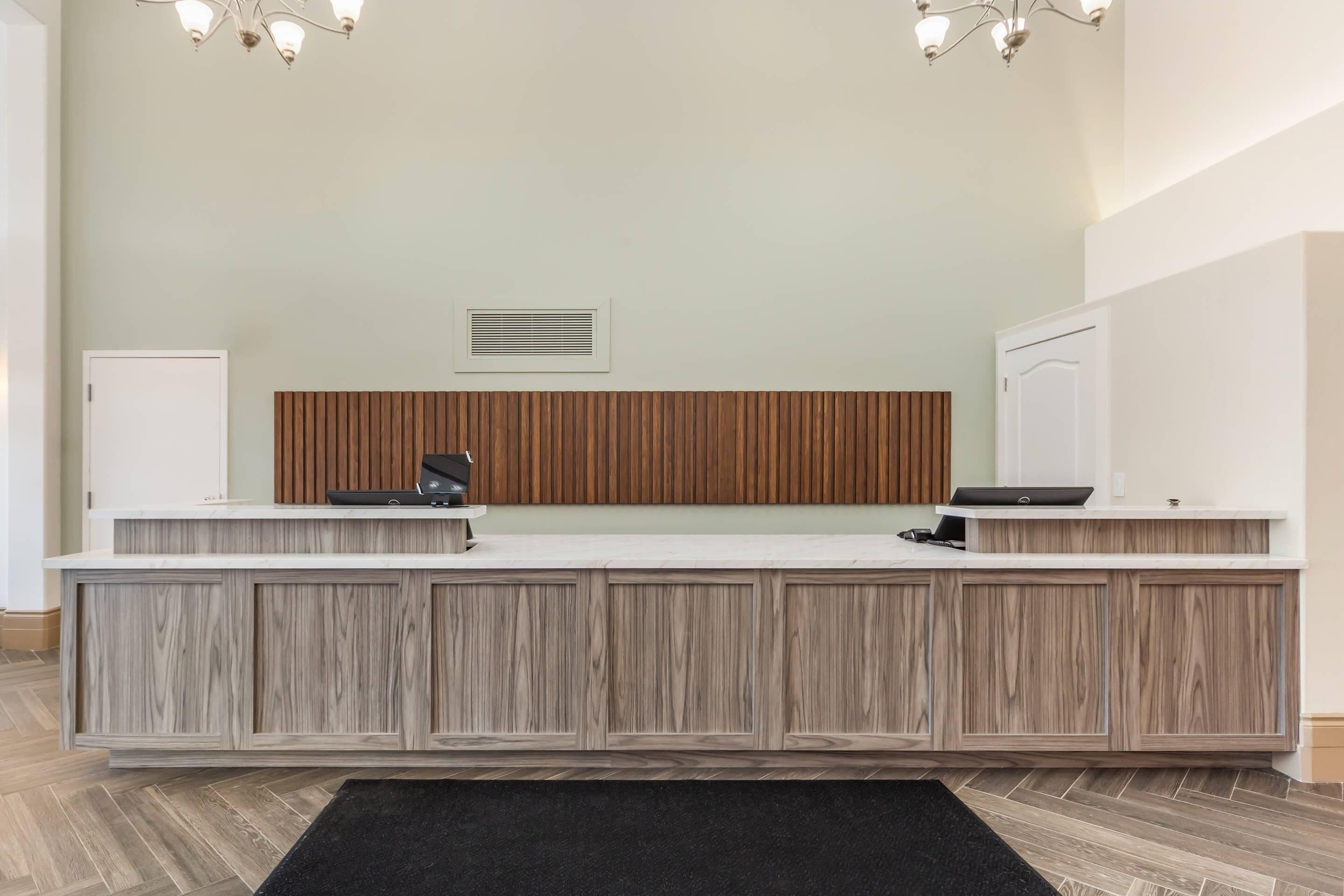 A reception desk with a wooden panel design, a white door, and a black rug.