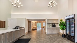 A hotel lobby with a reception desk, a refrigerator, a plant, and a seating area. - Velora Hinton, an Ascend Collection Hotel (Hinton)