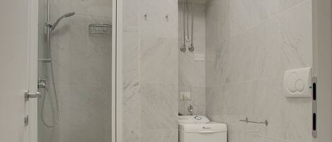 Ein modernes Badezimmer mit einer Glaskabine zur Dusche, einer integrierten Toilette und einem Waschbecken.