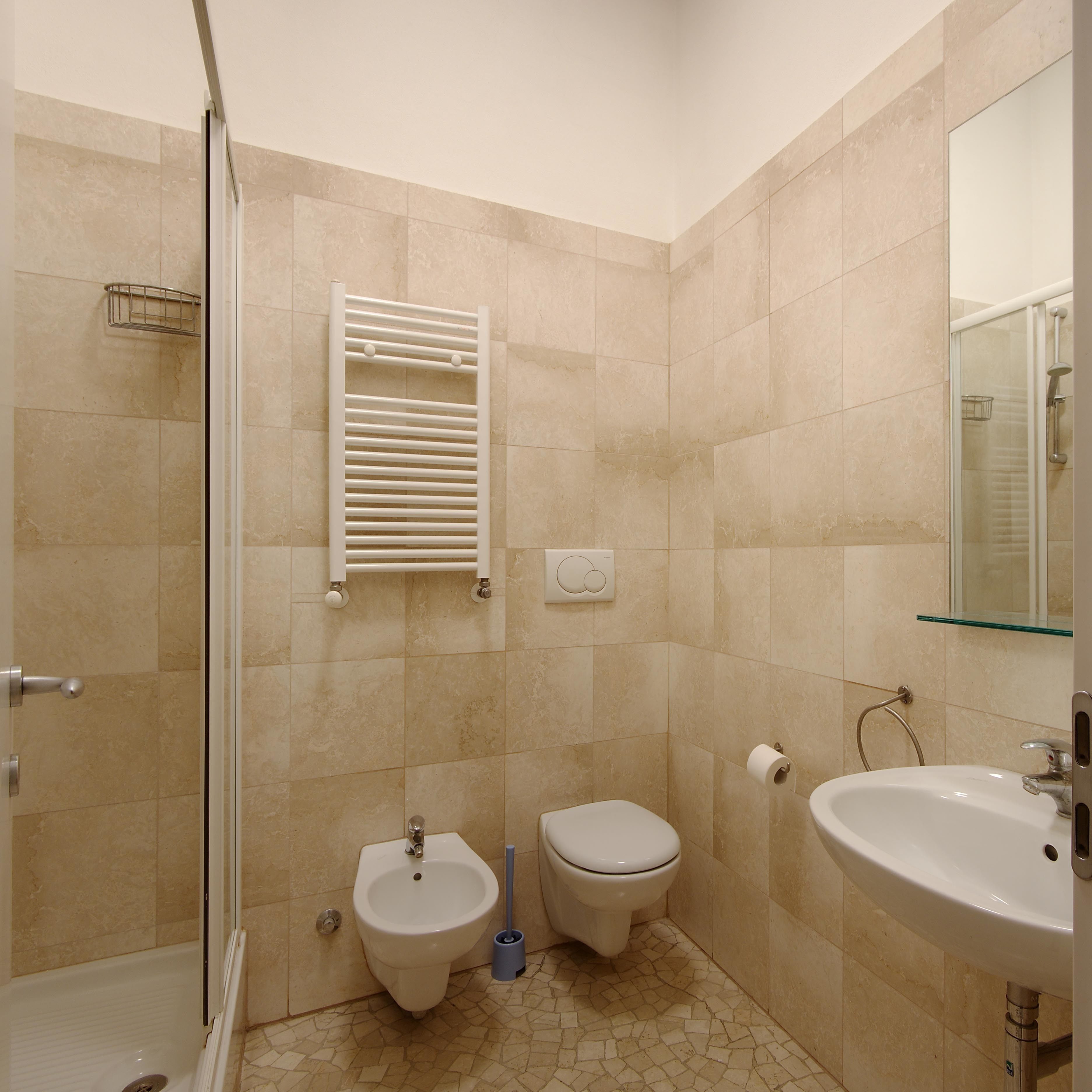 Un bagno con bidet, servizi igienici, lavandino e cabina doccia in vetro.