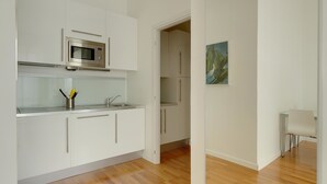 A modern kitchen with white cabinetry, a built-in microwave, and a wooden floor.