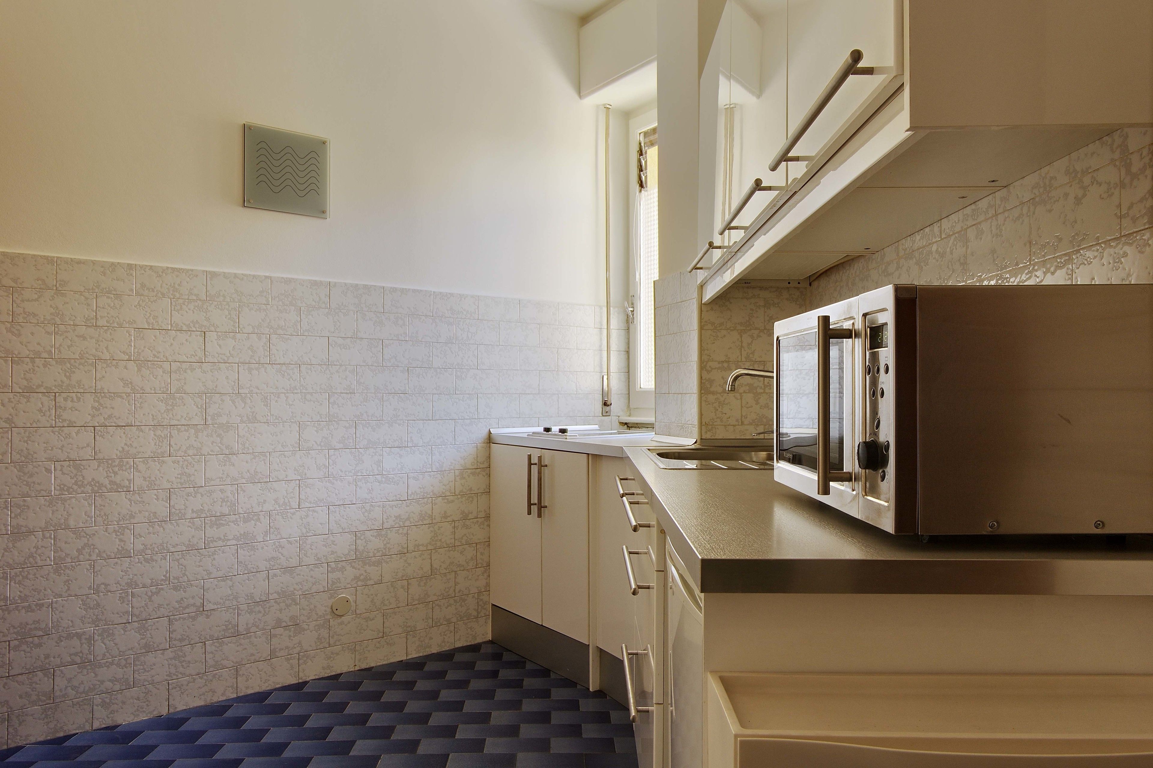 A kitchen with white cabinets, a stainless steel refrigerator, and a tiled backsplash.