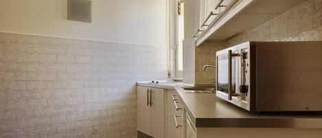 A kitchen with white cabinets, a stainless steel refrigerator, and a tiled backsplash.