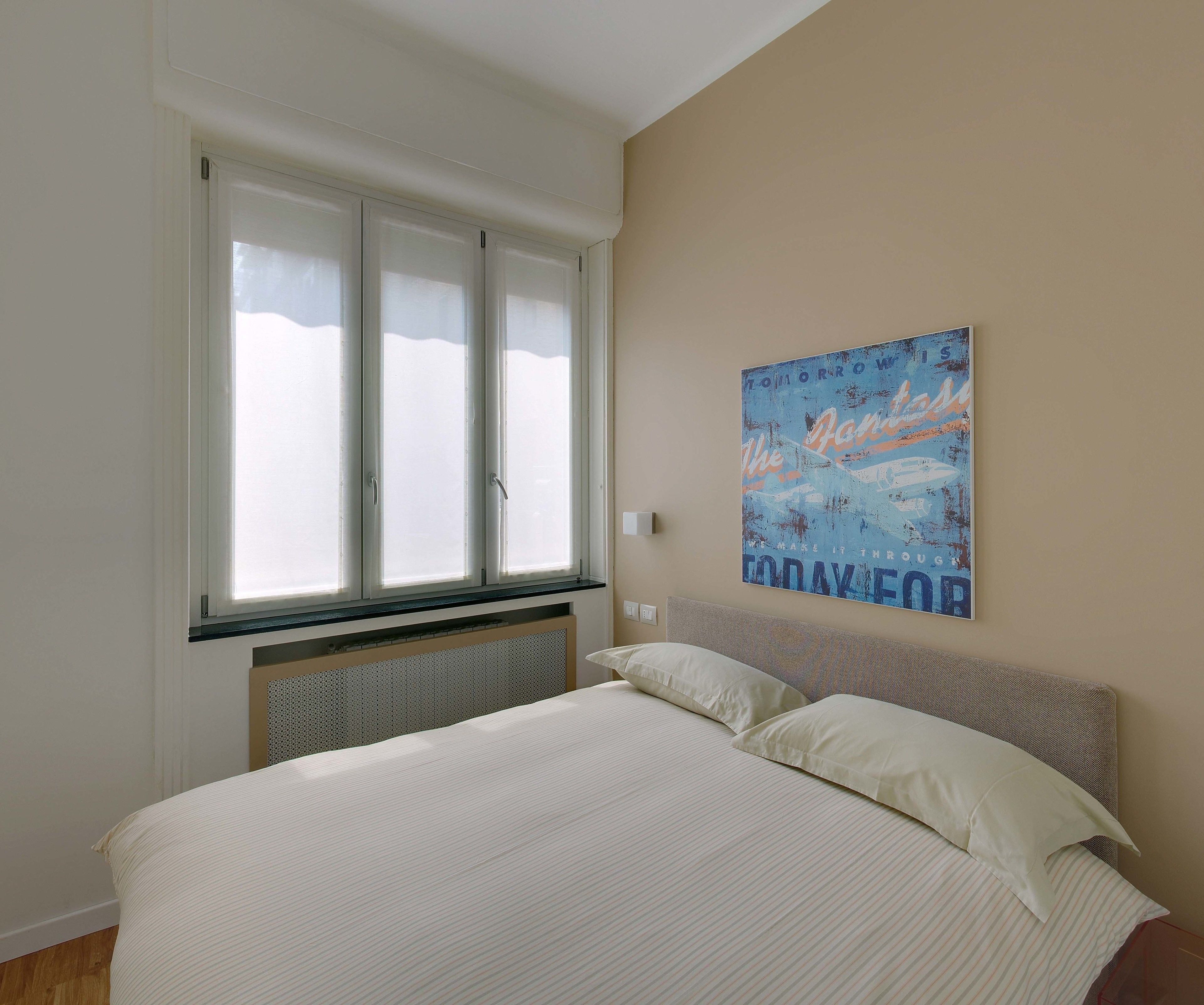 A bedroom with a large bed, a window with blinds, and a motivational poster on the wall.