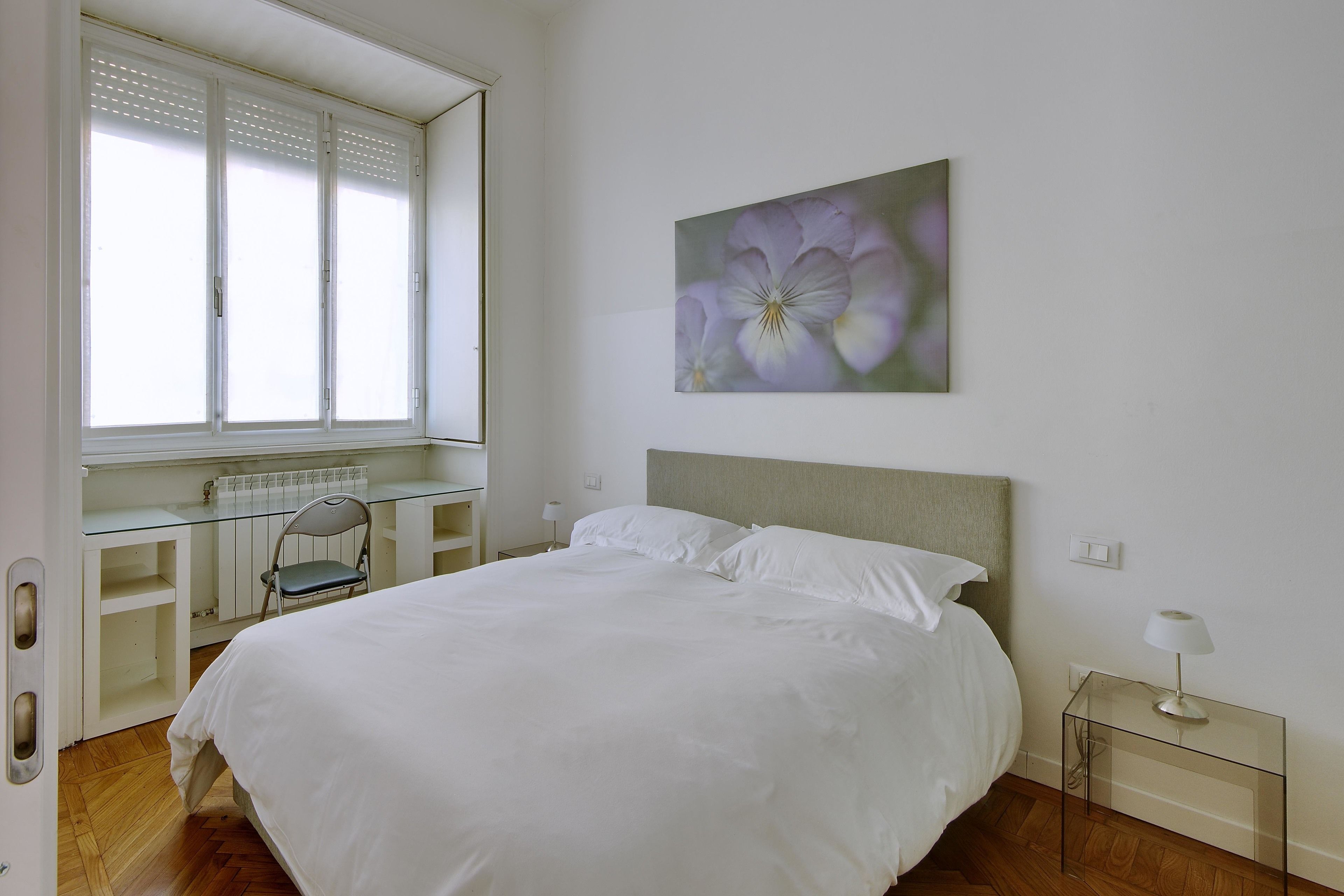A bedroom with a large bed, a desk, and a chair.