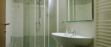 Un baño con inodoro, lavabo y ducha con mampara de vidrio.
