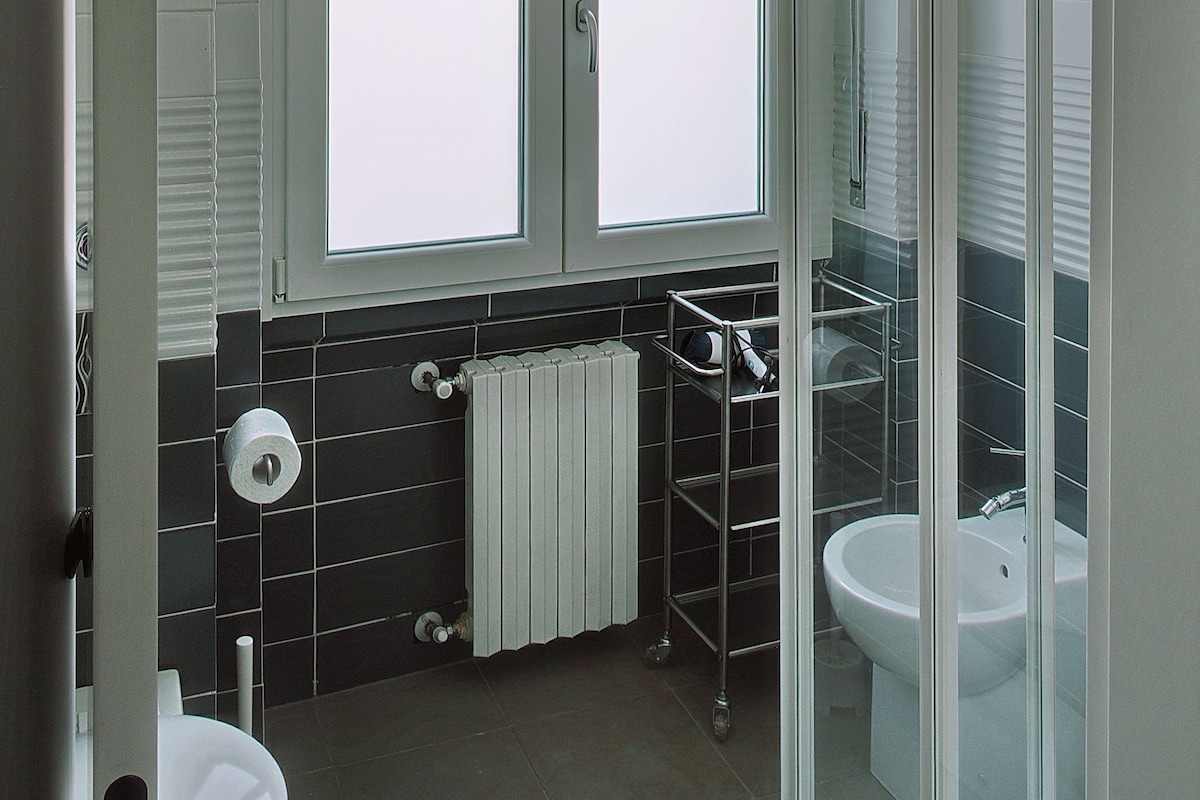 A bathroom with a toilet, a sink, a shower, and a window.