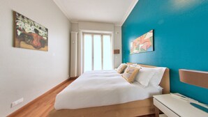 A bedroom with a bed, a nightstand, and a window with curtains.