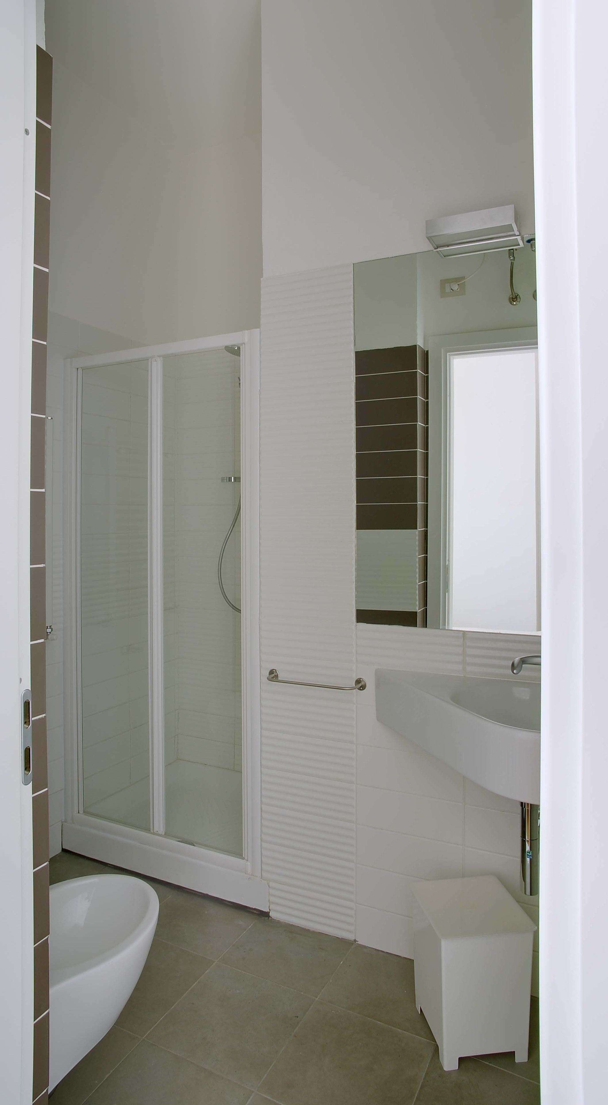 Une salle de bain avec une douche à parois de verre, un lavabo blanc et un miroir au-dessus du lavabo.