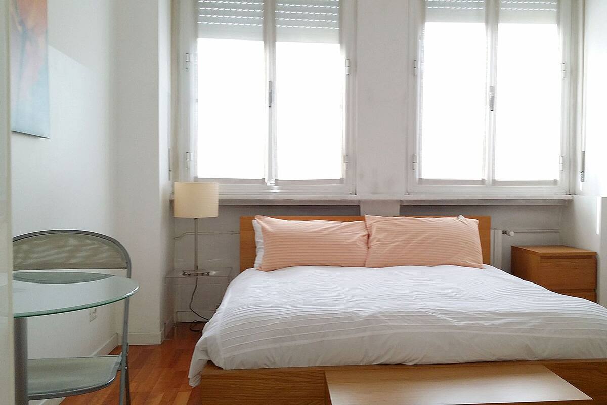 A bedroom with a bed, a desk, and a chair.
