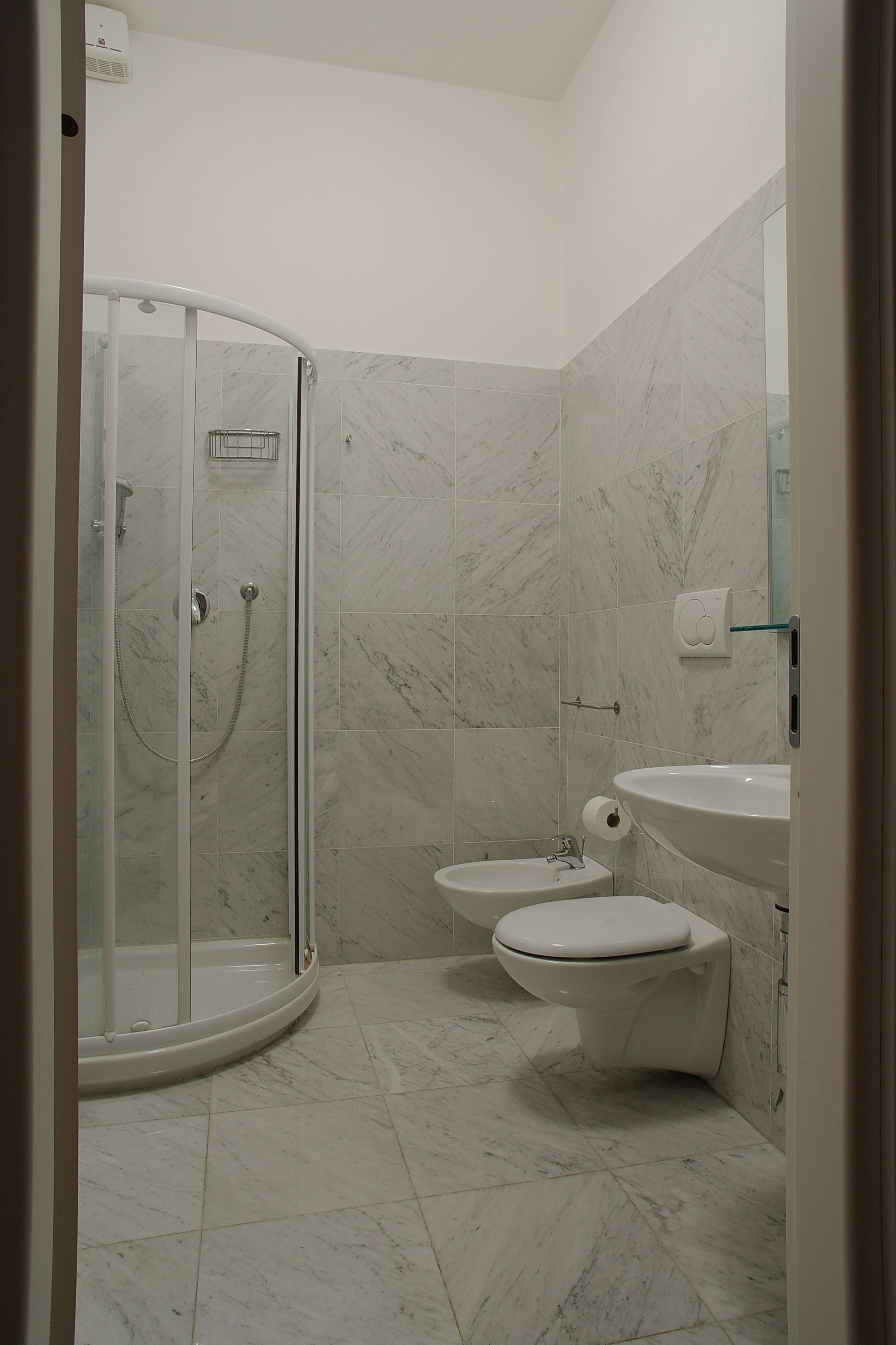 A bathroom with a glass-enclosed shower, a toilet, and a sink.
