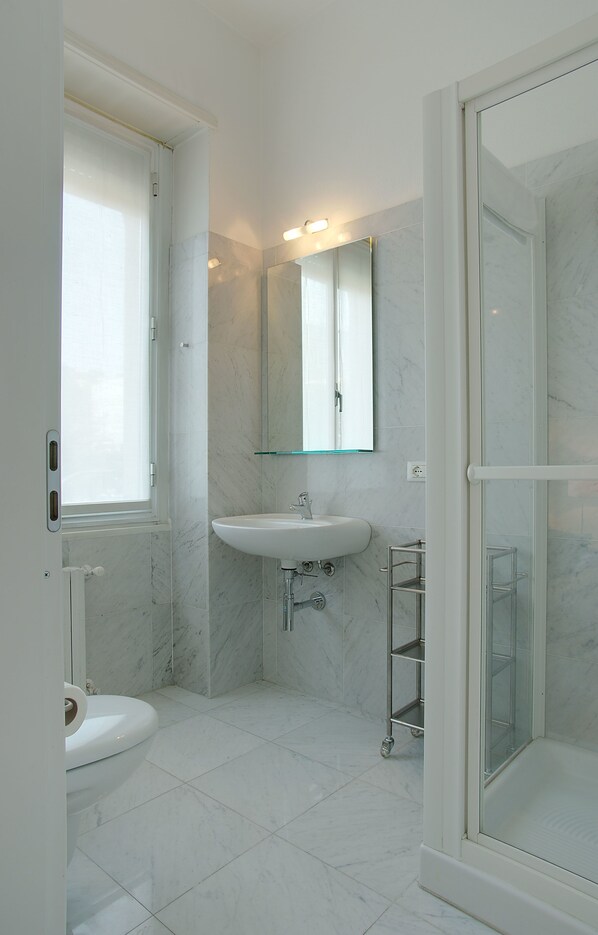A bathroom with a toilet, sink, and glass-enclosed shower.