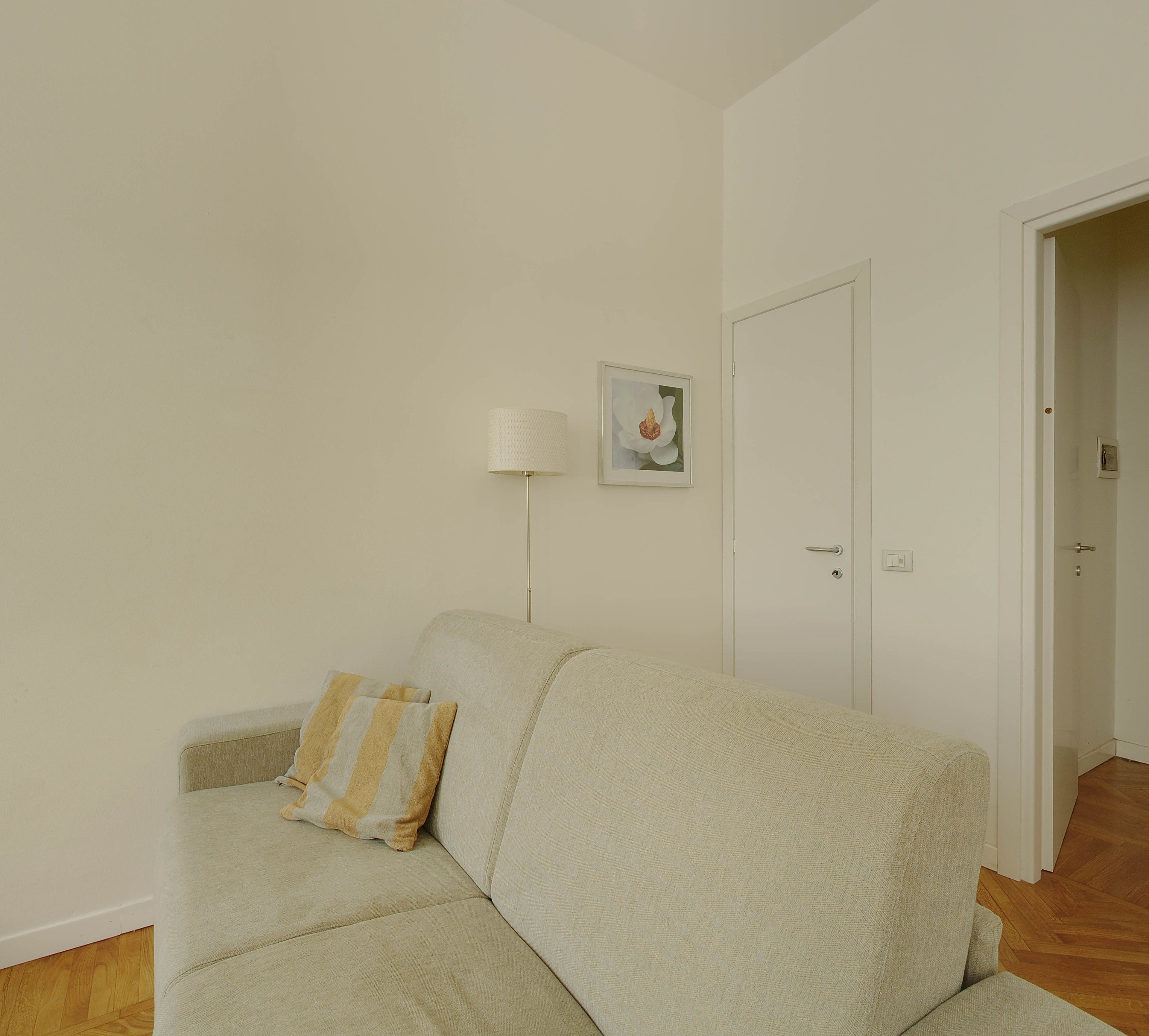 A living room with a sofa, a lamp, and a door.