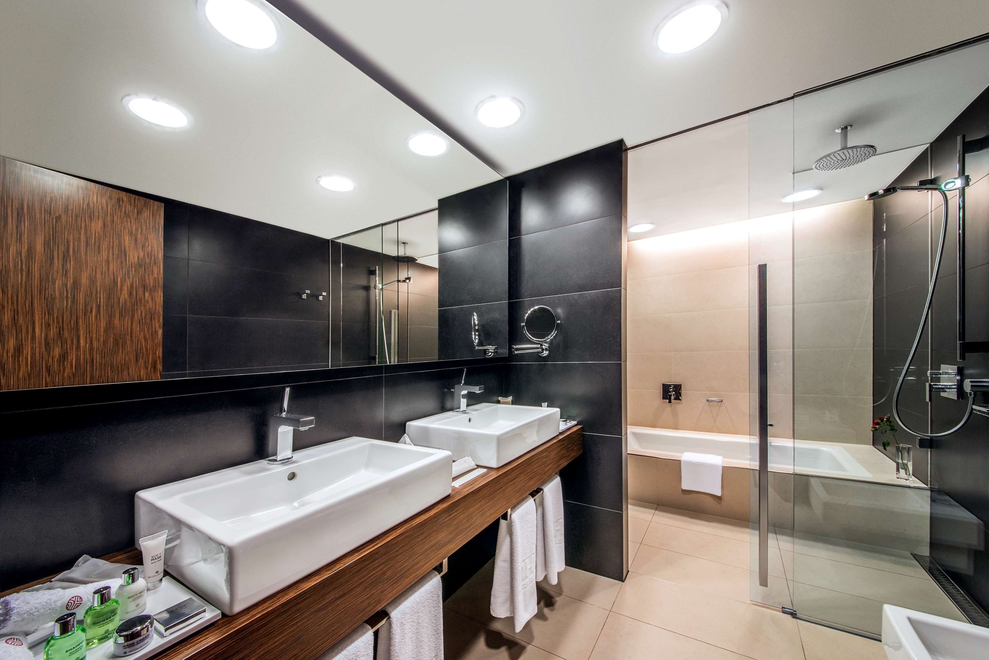 A modern bathroom with two sinks, a shower, and a glass-enclosed shower area.