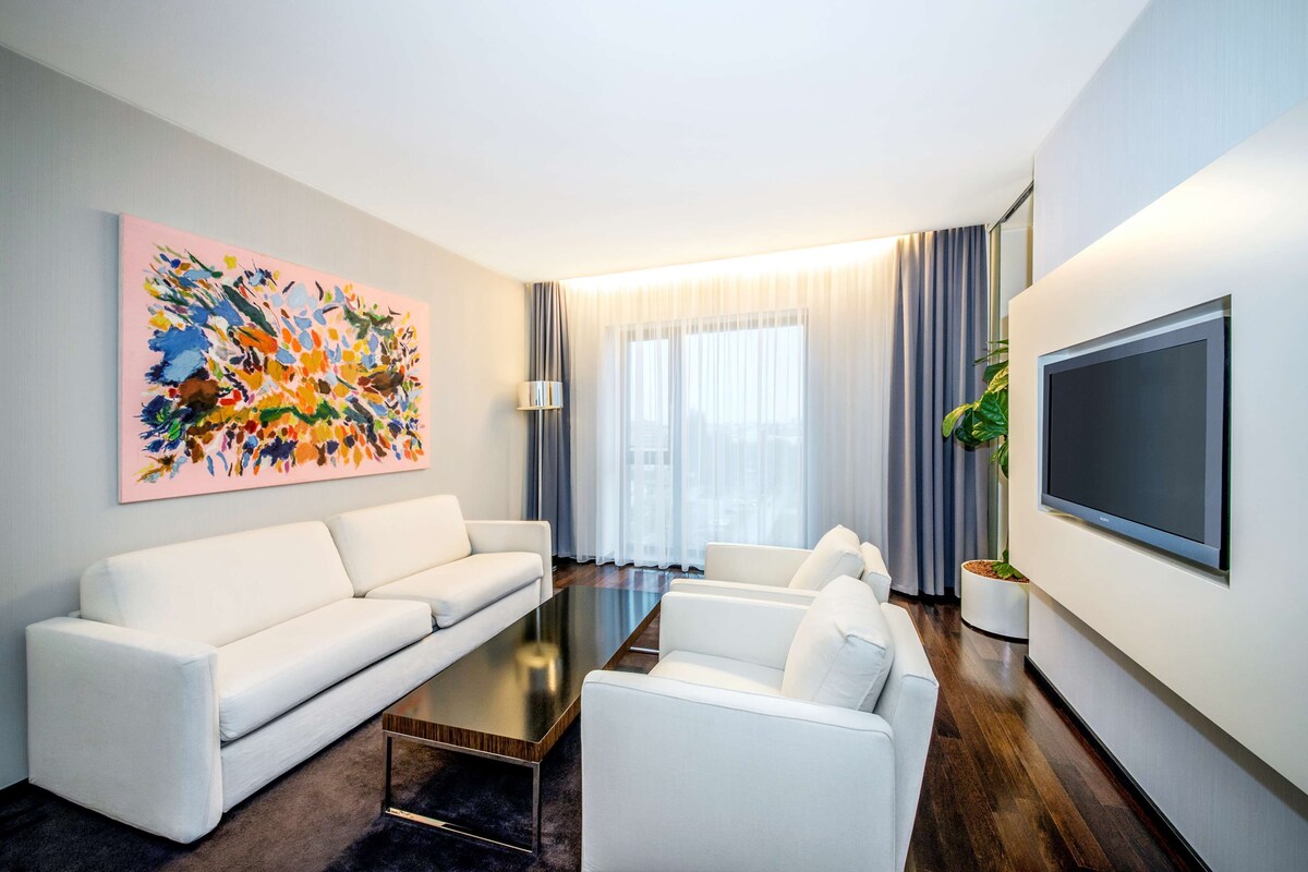 A modern living room with a white sofa, a coffee table, and a flat-screen TV mounted on the wall.