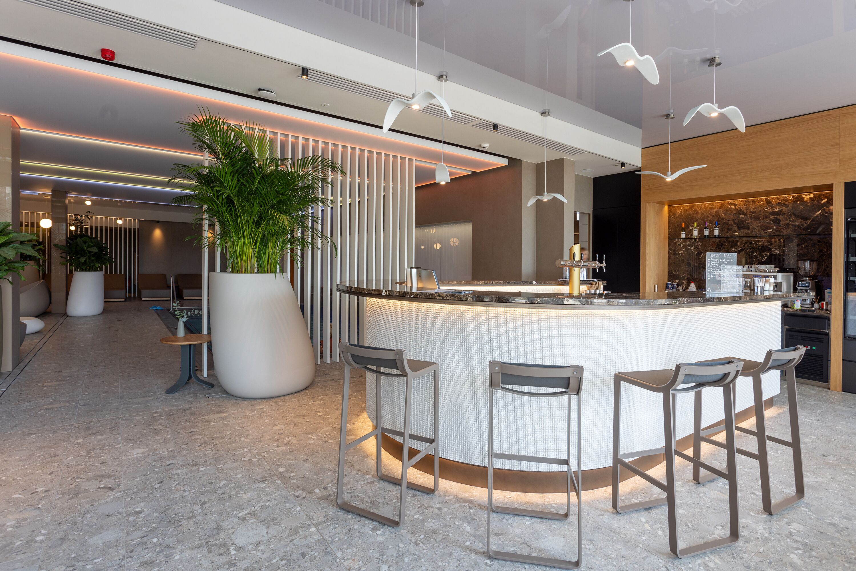 A modern bar area with a central island, bar stools, and pendant lighting.