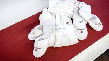 A set of white slippers and a towel with 'THE COLLECTION' text on a red and white striped surface.