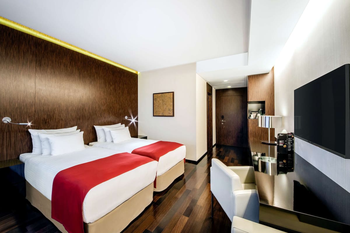 A hotel room with a large bed, a TV, and a desk with a chair.