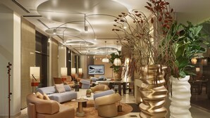 Un hall d’hôtel moderne, avec des canapés, une table basse et des plantes décoratives.