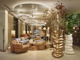 Un moderno vestíbulo de hotel con sofás, una mesa de centro y plantas decorativas.