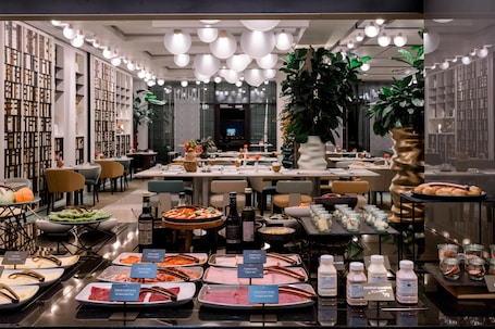 A buffet with various food options, a seating area, and a large plant in the center.
