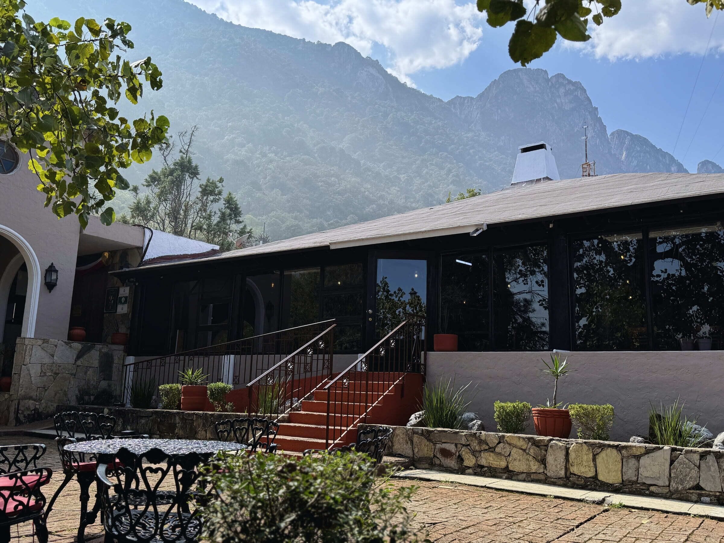 A building with a patio area, outdoor seating, and a staircase leading to a covered section.