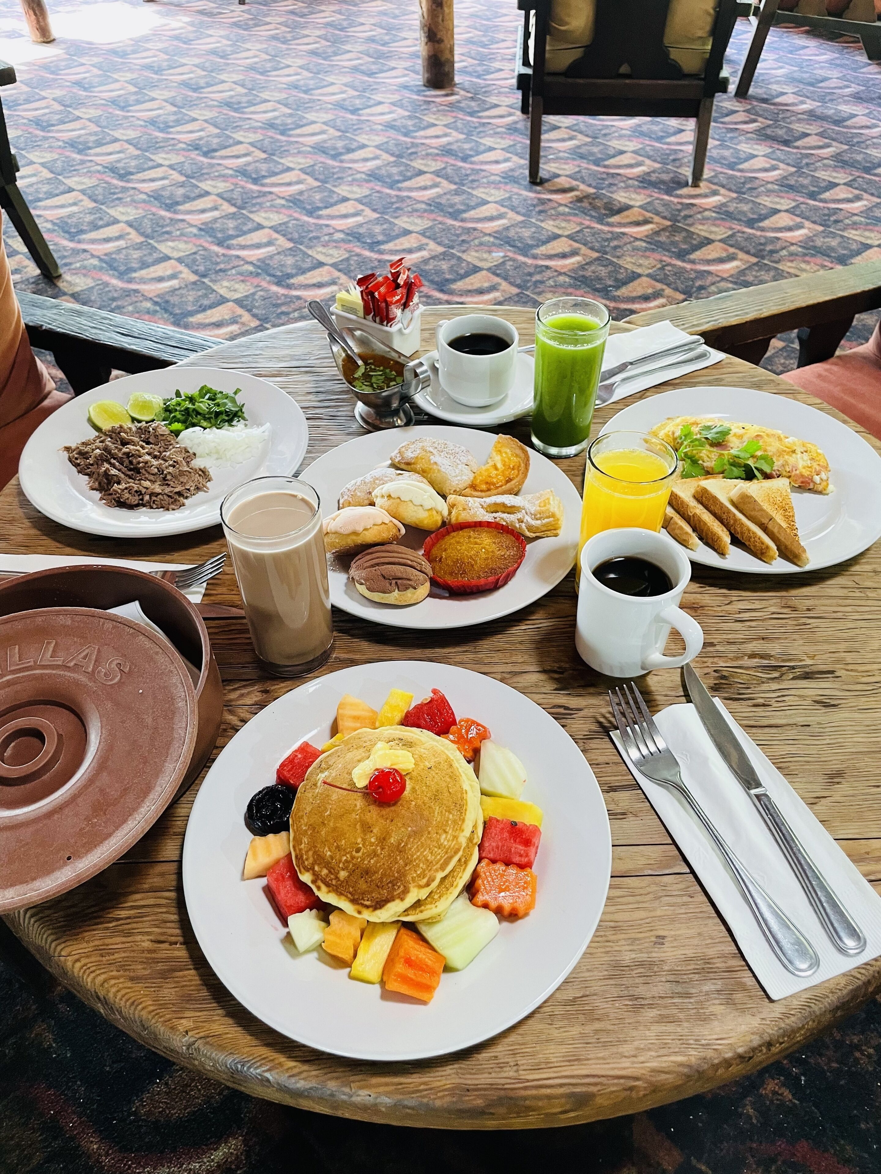 Una tavola imbandita per la colazione con pancakes, frutta e diversi prodotti.