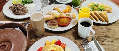 Una tavola imbandita per la colazione con pancakes, frutta e diversi prodotti.