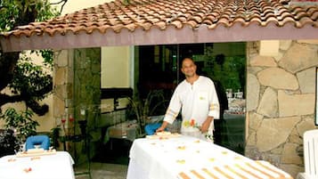 Guests can dine al fresco in this tranquil outdoor space, surrounded by lush greenery and a stone wall.