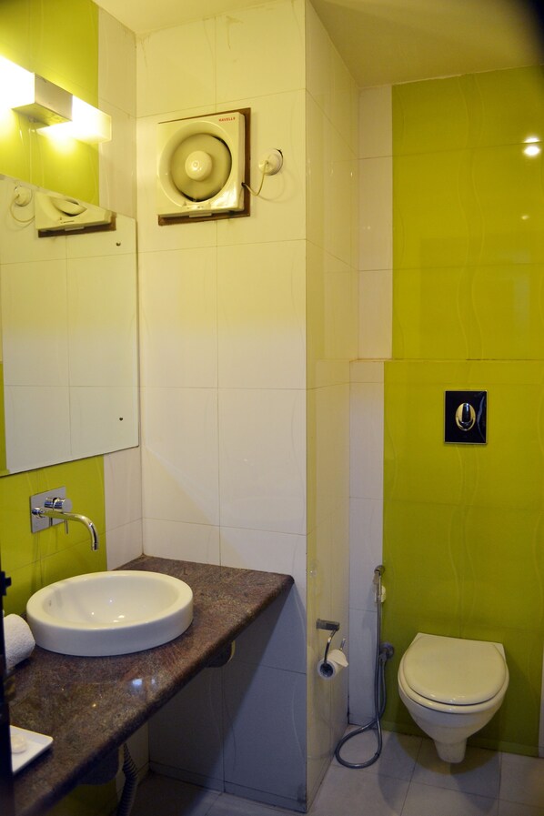 A bathroom with a sink, mirror, toilet, and a shower.