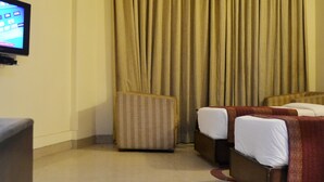 A hotel room with a bed, a small table, a chair, a television, and a ceiling fan.
