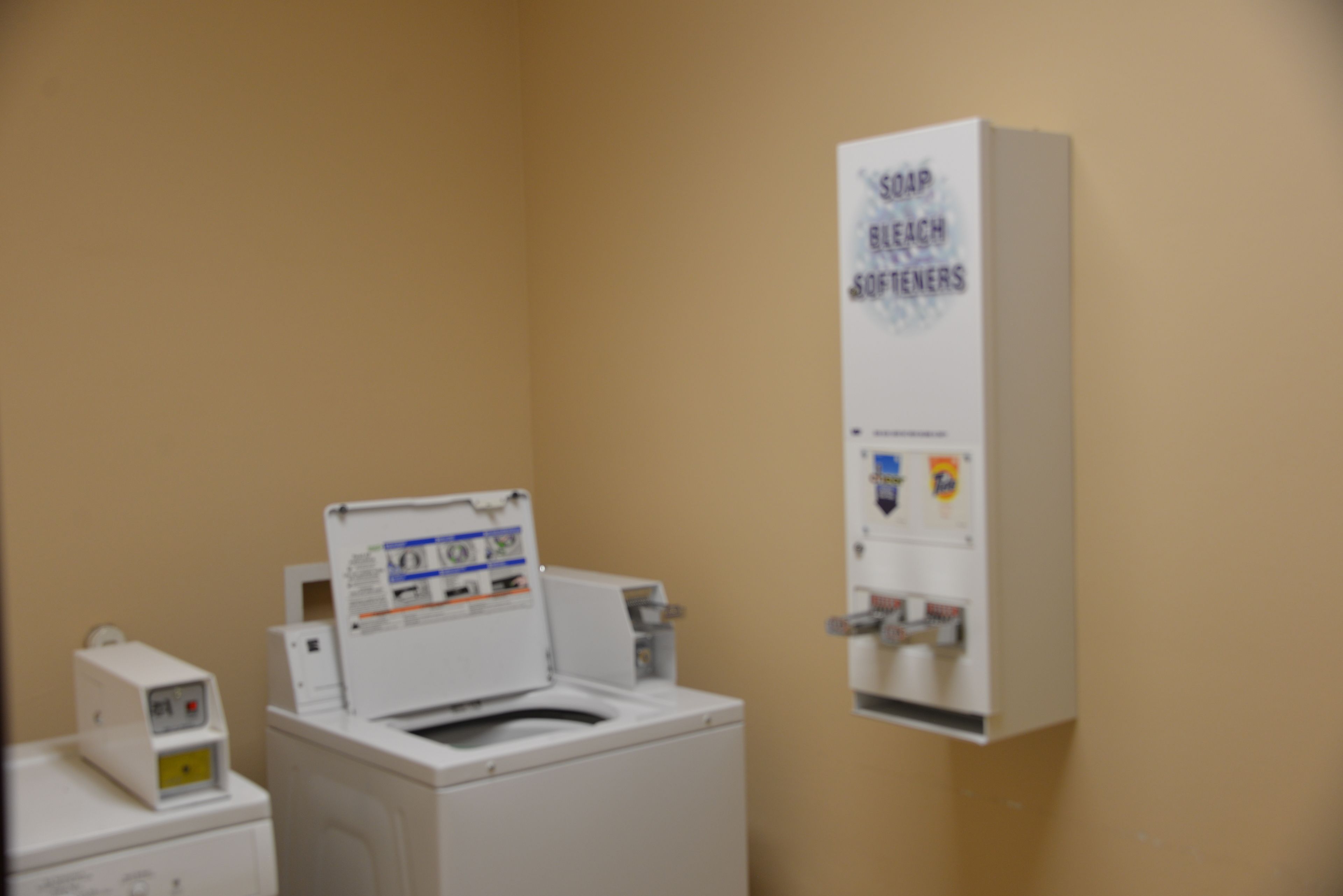 A laundry room with a washing machine, a dryer, and a soap dispenser.