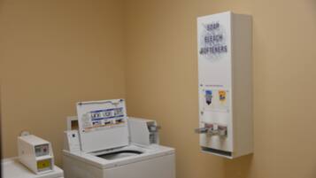 A laundry room with a washing machine, a dryer, and a soap dispenser.