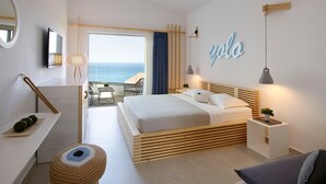 Une chambre à coucher moderne, avec un lit, des tables de chevet, un petit tabouret, un bureau et une vue sur l’océan.