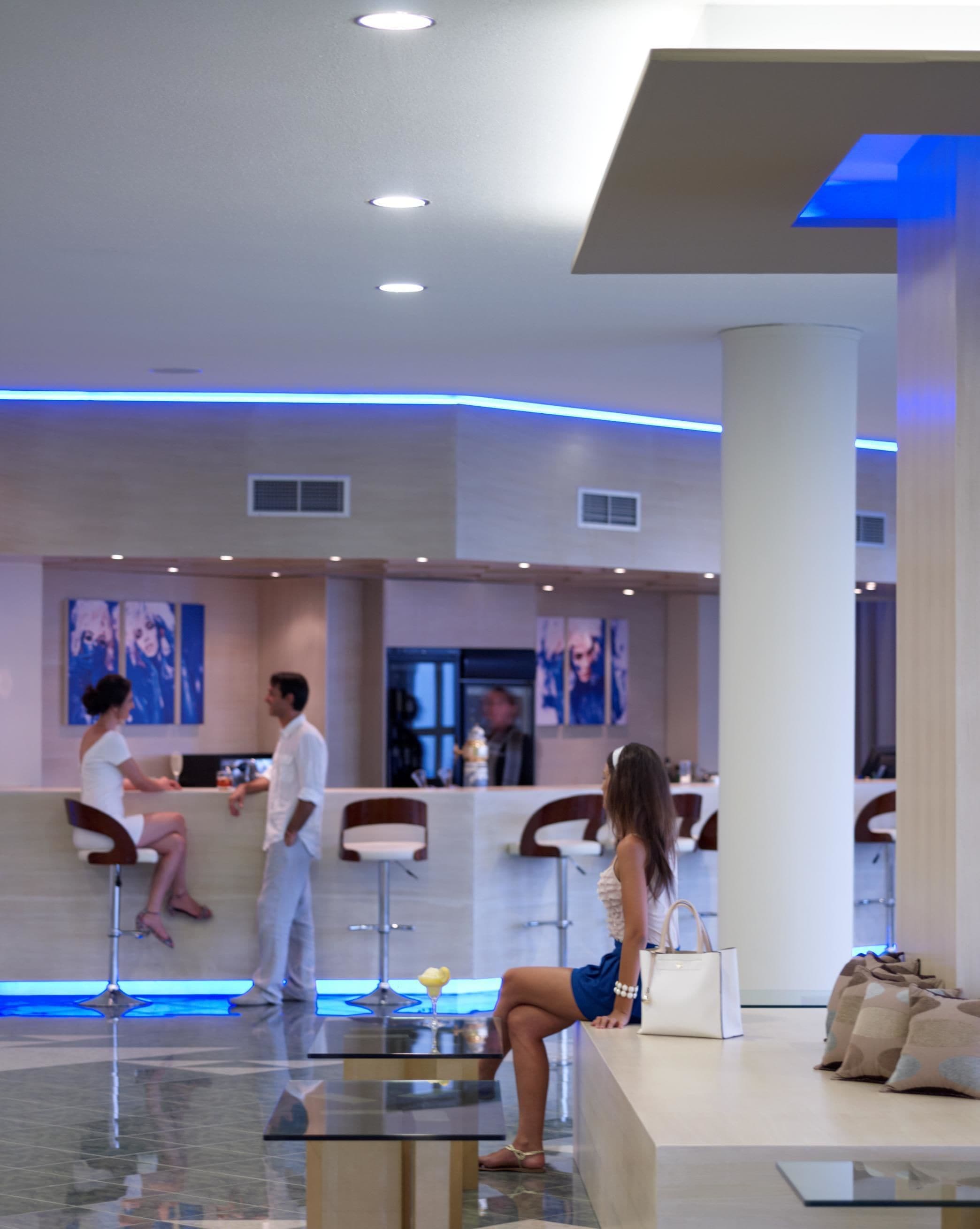 A modern lobby with a reception desk, seating areas, and a glass coffee table.