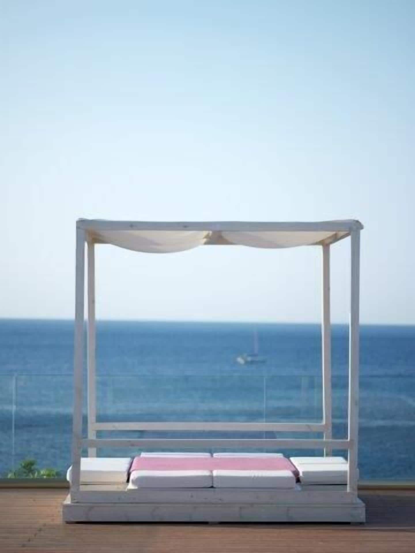 A white outdoor seating area with a view of the ocean.
